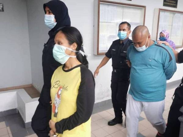 Zuraida (depan) dan Mohd Fadzli (kanan) dibawa anggota polis keluar dari Mahkamah Majistret Ayer Keroh, Melaka pada Isnin.