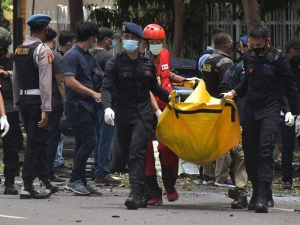 Anggota polis mengangkat cebisan mayat suspek di depan Gereja Katedral Makassar, Sulawesi Selatan, Indonesia pada Ahad. 