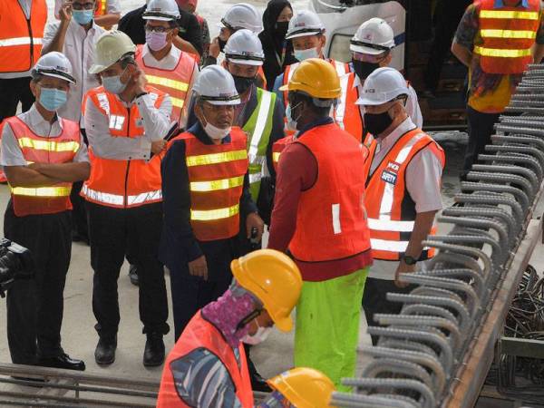 Tajuddin mendengar penerangan daripada salah seorang petugas semasa meninjau kemajuan projek Transit Aliran Ringan (LRT) Laluan 3 (LRT3) pada sesi lawatan kerja di ‘U-Trough Casting Yard’ di Bandar Saujana Putra, Kuala Langat pada Isnin. - FOTO: BERNAMA