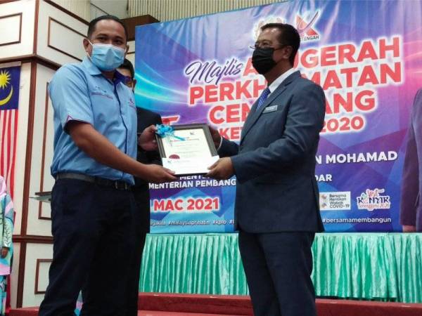 Abdul Rahman (kanan) menyampaikan sijil kepada salah seorang daripada penerima Anugerah Perkhidmatan Cemerlang Ketengah 2020, di Balai Orang Ramai (BALORA) Bandar AL Muktafibillah Shah, Dungun, pada Rabu.