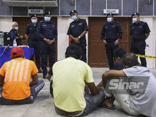 Zainudin (empat dari kanan) bertanya sesuatu kepada suspek yang ditahan dalam operasi khas di Felda Jelai, Tampin pada malam Rabu.