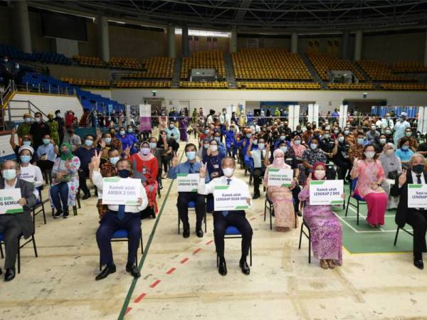 Muhyiddin (tengah) dan isteri, Puan Sri Noorainee Abdul Rahman bergambar dengan orang ramai yang menerima suntikan vaksin ketika melawat Pusat Vaksinasi Covid-19 di Stadium Perpaduan hari ini. - Foto Bernama