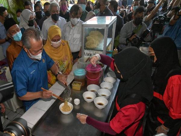 Muhyiddin (kiri) cuba bakat membuat mi kolok sebelum bersarapan di Restoran Sepinang Sari di Jalan Satok, hari ini. Foto Bernama