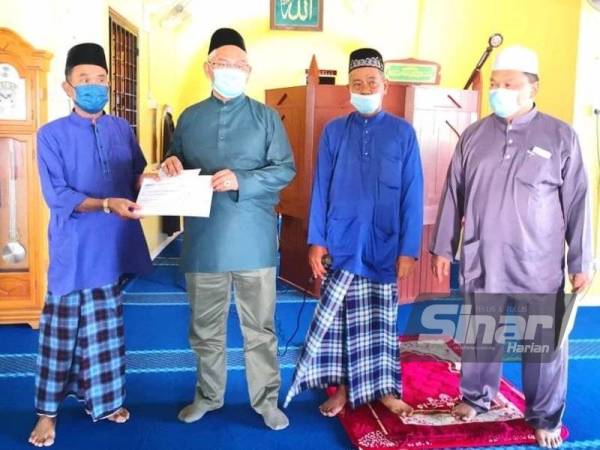 Noh (dua dari kiri) menyampaikan cek kepada wakil masjid pada Majlis Penyampaian Sumbangan kepada Masjid Al-Iman Tali Air 2 Ban 3 pada Jumaat.