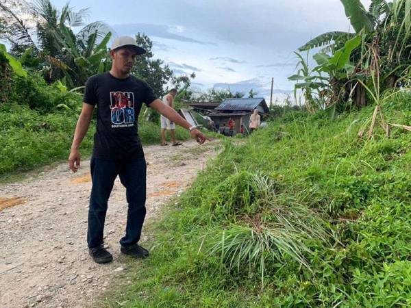 Seorang daripada adik-beradik mangsa menunjukkan tempat mangsa ditemukan dengan kesan kelar di leher dan tikaman di rusuk kanan depan rumahnya di Kampung Desa Makmur, Majidee di sini pada Jumaat.