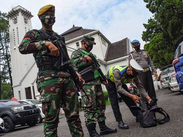 Anggota keselamatan turut melakukan pemeriksaan ke atas barangan milik individu yang mahu memasuki gereja di Bandung, Jawa Barat pada Jumaat. - Foto: AFP