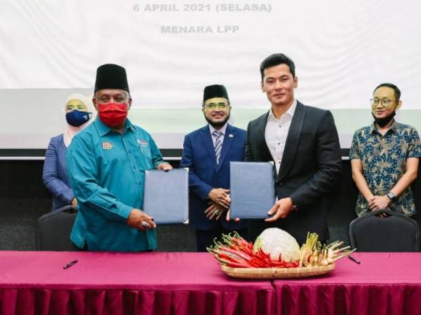 Abdul Razak (kiri) dan Mohd Firdaus (kanan) menunjukkan dokumen yang ditandatangani sambil diperhatikan oleh Nik Muhammad Zawawi pada Majlis Menandatangani Memorandum Persefahaman antara PPK Kuala Langat dan AGPGM yang diadakan di Menara LPP, Kuala Lumpur pada Selasa.