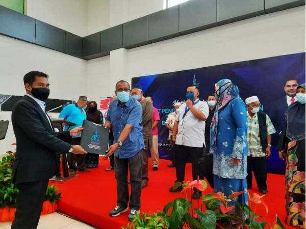 Hamdan (kiri) menyampaikan permit kepada 19 penganjur bagi menjalankan aktiviti di bazar Ramadan dan Aidilfitri di Lobi Kompleks MBK pada Rabu.