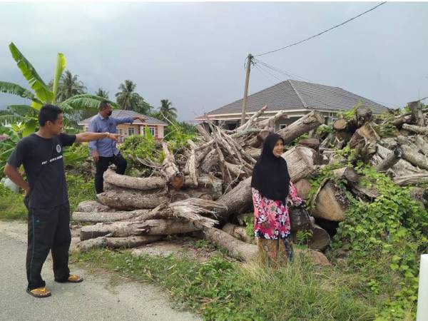 Hasmah (kanan) menunjukkan longgokan sisa kayu yang dikhuatiri menjadi sarang haiwan liar dan berbisa di Jalan Dulang-Kampung Teroi, di Yan pada Khamis.