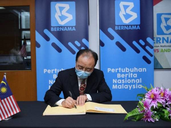 Duta Besar China ke Malaysia Ouyang Yujing menandatangani buku pelawat ketika melawat Wisma Bernama hari ini. -Foto Bernama