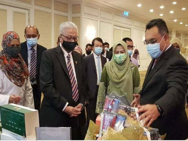 Ismail Sabri dan Noraini melihat produk yang dihasilkan daripada madu kelulut pada majlis pemeteraian perjanjian antara Pharmaniaga dan UMT di Hotel Royale Chulan Damansara pada Jumaat.