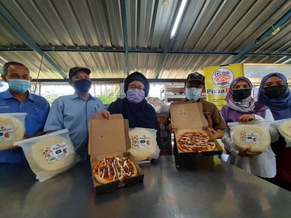 Che Abdullah (tiga dari kanan) bersama Nur Adila (dua dari kanan) menunjukkan pizza yang diusahakan usahawan muda tersebut di Kubang Semang, Bukit Mertajam pada Jumaat.