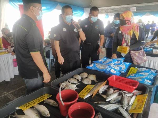 Azman (dua dari kiri) mempromosikan jualan Q'Fish pada Pelancaran Program Jualan Prihatin Rakyat di pekarangan Pasaraya Mydin Taman Saga pada Sabtu.