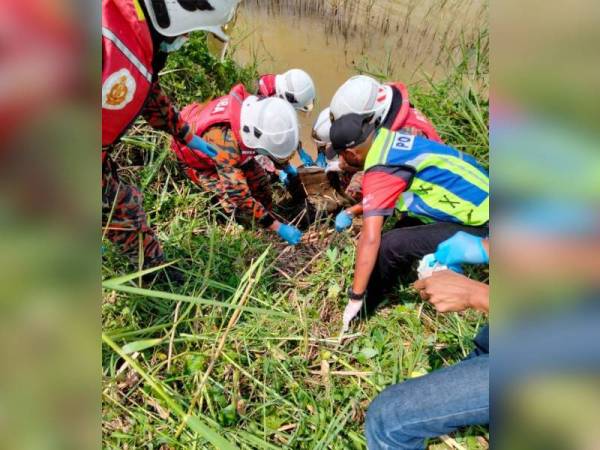 Anggota bomba dan polis yang terlibat dalam pencarian mengangkat mayat mangsa yang ditemui dalam terusan. - Foto Ihsan PDRM.