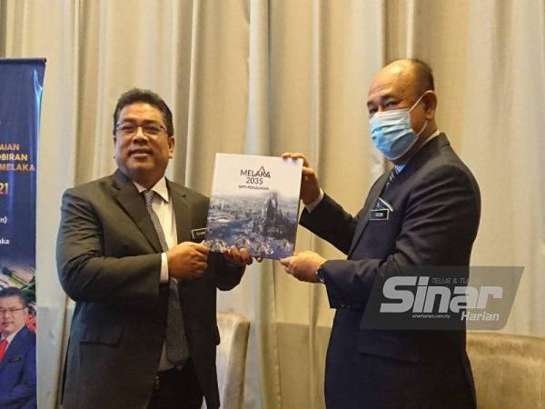 Sulaiman (kiri) dan Hasim menunjukkan 'Coffee Table Book' Melaka 2035 selepas selepas menyempurnakan Majlis Pencapaian Setahun Pentadbiran Kerajaan Negeri Melaka 2020-2021di Hotel Hatten, di Banda Hilir, di sini pada Isnin.