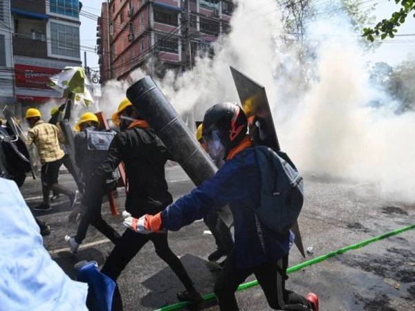 Penunjuk perasaan anti rampasan kuasa tentera menyelamatkan diri selepas pihak berkuasa melepaskan gas pemedih mata di Yangon - Foto AFP