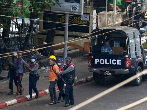 Polis menahan orang awam di Yangon, Myanmar pada 27 Februari 2021. Sekurang-kurangnya 71 wartawan ditahan pihak berkuasa Myanmar sejak rampasan kuasa tentera pada Februari lalu. - Foto AFP