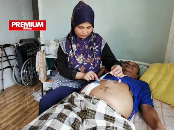 Roziana menunjukkan perut suaminya yang ditebuk untuk saluran wayar bagi rawatan dialisis.