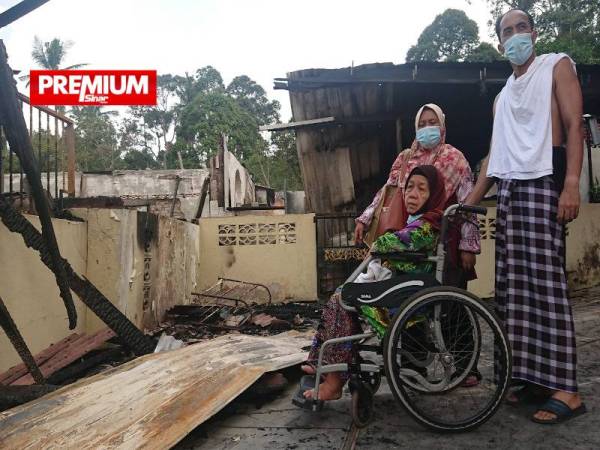 Nurisah (tengah) bersama anak dan menantunya melihat rumah pusaka berusia lebih 80 tahun musnah dijilat api dalam kejadian awal pagi Khamis.