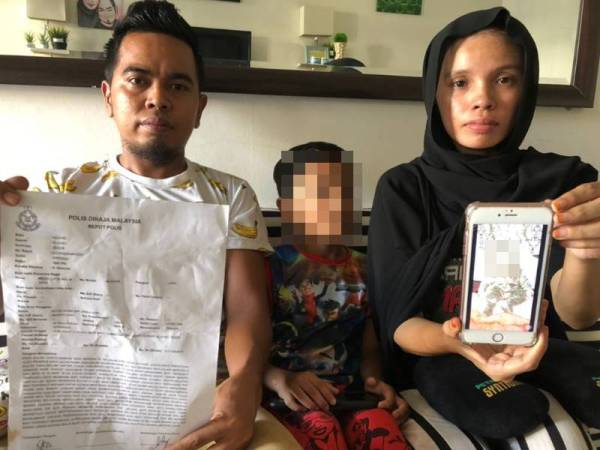 Mohd Nizam (kiri) dan isterinya menunjukkan laporan polis serta gambar bayi angkatnya yang dipercayai mati didera di rumahnya di Taman Gunung Selatan, Kluang pada Ahad.