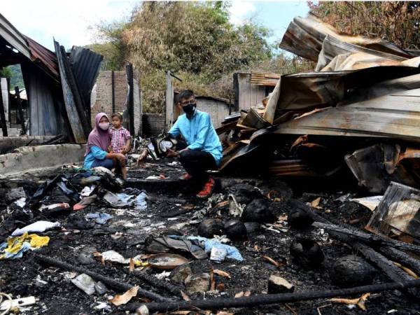 Effandy bersama isterinya, Salbilla dan anaknya Nuur Zulaieca memerhatikan rumah pusaka keluarga mereka yang musnah dalam kebakaran pada 6 April lalu.  - Foto Bernama