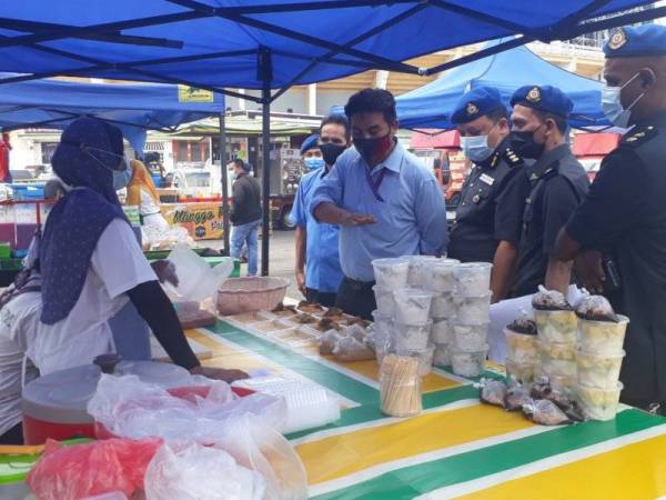 Rae Morn (empat kanan) memberikan nasihat kepada seorang peniaga semasa turun membuat pemantauan di bazar Ramadan Stadium Darul Aman pada Rabu.