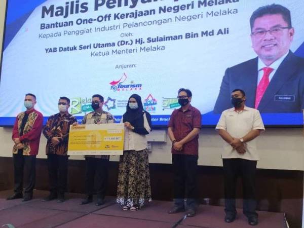 Sulaiman (empat dari kanan) menyampaikan sumbangan kepada salah seorang penerima pada Majlis Penyampaian Bantuan One-off Kerajaan Negeri di Hotel MITC, Ayer Keroh pada Khamis.