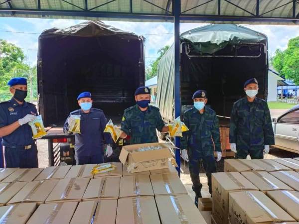 Azhari (tengah) menunjukkan minyak masak peket yang berjaya dirampas oleh PGA Batalion 7 Kuantan di sebuah kedai di Kampung Salor, Kota Bharu.