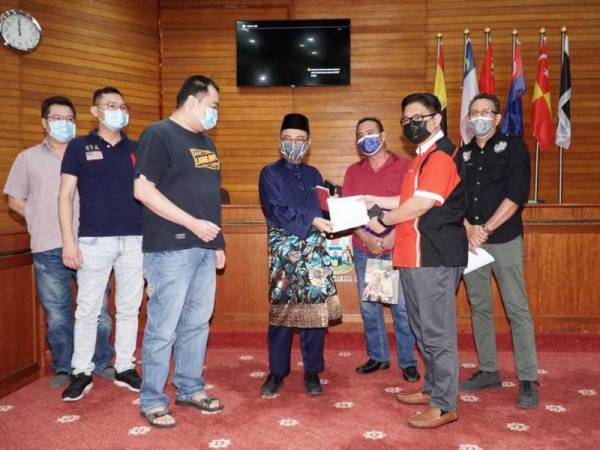 Rumaizi (empat dari kiri) menerima kertas cadangan daripada sebuah NGO yang hadir pada pertemuan bersama isu peniaga ais di Pasar Borong Ipoh.