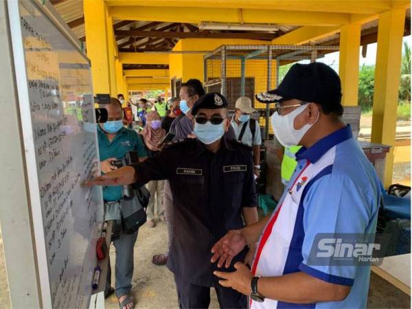 Shafien (kanan) mendengar taklimat awal dari Ketua Polis Daerah Kota Bharu, Asisten Komisioner Abdul Rahim Daud di jeti berkenaan.