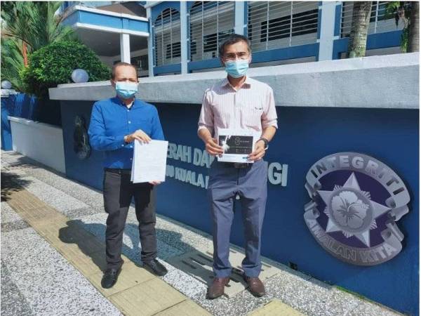 Hamdan (kanan) bersama seorang lagi wakil Kramat menunjukkan salinan laporan polis di depan IPD Dang Wangi, Kuala Lumpur pada Sabtu.