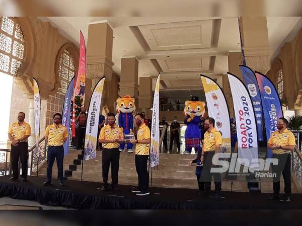 Ahmad Shapawi (tiga dari kiri) menyampaikan cenderahati kepada Onn Hafiz pada Flag Off Program Road To Tokyo di lobi Bangunan Dato' Jaafar Muhammad, Johor Bahru pada Ahad.