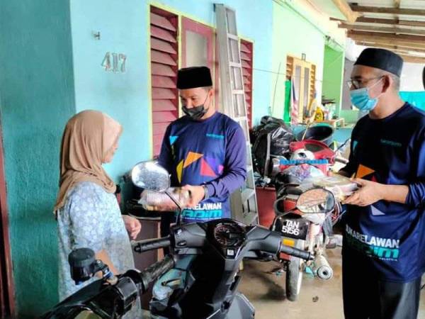 Salah seorang asnaf di Marang menerima sumbangan ayam golek sebagai juadah berbuka puasa yang disampaikan Nasrul Hadi (tengah).