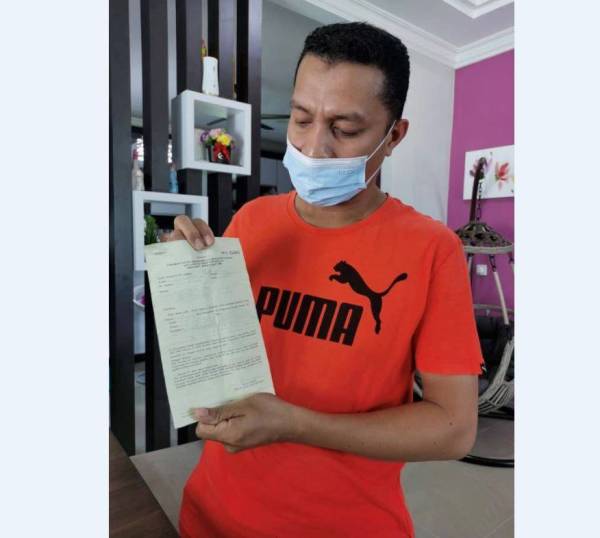 Peniaga burger, Wan Mohd Faisal Wan Kadir, 38, menunjukkan notis kompaun RM50,000 yang dikenakan terhadapnya pada Isnin.