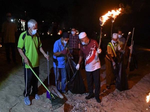 Ariffin (tiga, kiri) turun padang bersama para peserta mengutip sampah di sekitar pantai pada Program Bersih Pantai Ramadan anjuran Pejabat Daerah Marang di Pantai Kelulut malam tadi.