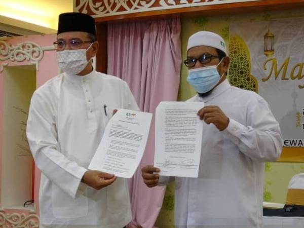 Wan Rosdy (kanan) dan Rosli (kiri) menunjukkan isi perjanjian dalam MN mengenai pengagihan kerusi DUN di Pahang di Dewan Kediaman Rasmi Menteri Besar Pahang di sini pada malam Rabu.