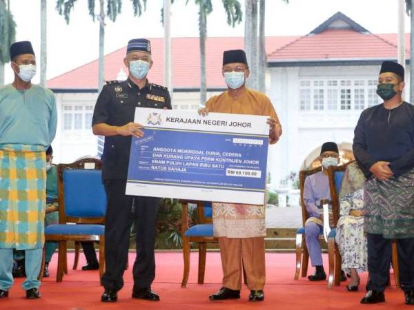 Hasni (dua dari kanan) menyerahkan replika cek kepada wakil PDRM Johor pada majlis berbuka puasa dan penyerahan zakat dari syarikat swasta, anak syarikat kerajaan negeri di kediaman rasmi Menteri Besar, Saujana, Johor Bahru pada Rabu.