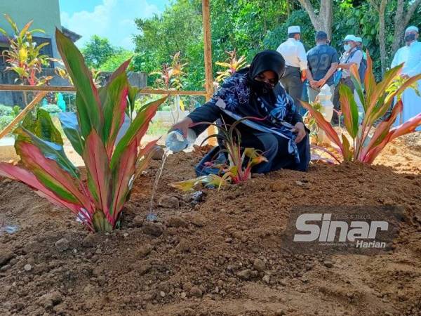 Rumaini menyiram air mawar pada kubur Allahyarham suaminya, Md Yusnan yang selamat dikebumikan di Tanah Perkuburan Islam Pondok Haji Hassan, Ketereh pada Jumaat.