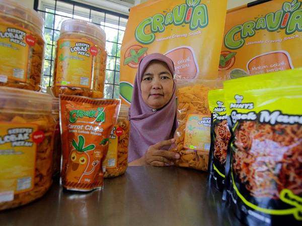 Pengeluar makanan ringan Nini Dzuraini Abdullah bersama produk makanan ringan kerepek lobak merah 'Cravia'. - Foto Bernama