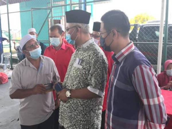 Noh (dua dari kanan) menyampaikan sumbangan kepada salah seorang pesawah di Gelanggang Futsal Kampung Seri Tiram Jaya di sini pada Khamis.