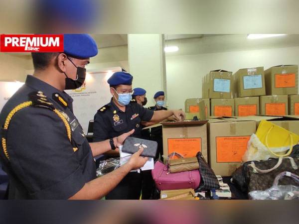 Zubir menunjukkan antara dompet tiruan yang dirampas dalam serbuan di Jalan Petaling, Kuala Lumpur pada Selasa.