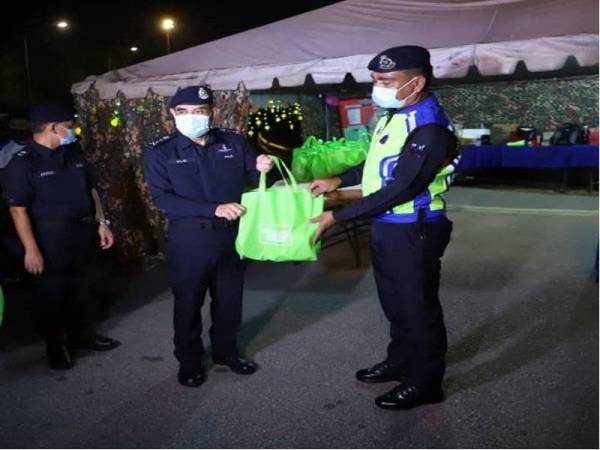 Abdul Majid (dua dari kanan) menyampaikan pek makanan beserta kuih raya kepada salah seorang anggota polis yang bertugas di SJR Tol Ayer Keroh, pada Sabtu.