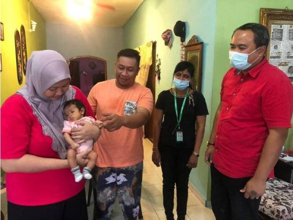 Shahrizan (dua kiri), Azah Fazazillah dan anak mereka, Qish Naura Syifa yang menghidap penyakit jantung berlubang dan saluran kemaluan serta najis yang bercantum menerima bantuan daripada Mohd Fadel dan Pengurus Econsave Cawangan Kluang, V Kasturi Bai di Sri Lalang Kluang, pada Sabtu.