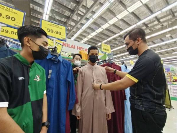 Muhammad Asree membantu seorang daripada 35 anak yatim memilih baju raya sempena program Cahaya Aidilfitri GPMS Perak di Mydin Manjoi, Ipoh pada Sabtu.