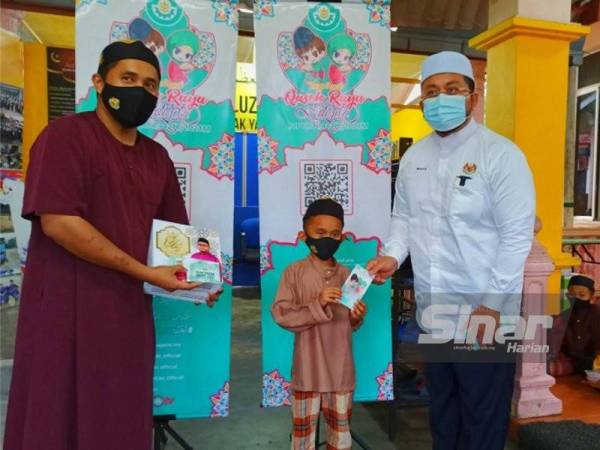 Ahmad Marzuk (kanan) menyerahkan sumbangan ringkas kepada anak-anak yatim di Madrasah Al Uzma Lil Aitam, Kampung Chekok, Kota Bharu.