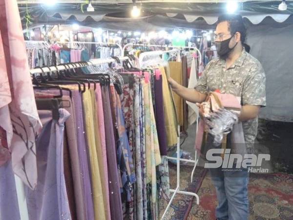 Mohd Nor Azrul menyusun pakaian yang dijual pada separuh harga di Bazar Aidilfitri Bukit Sekilau.