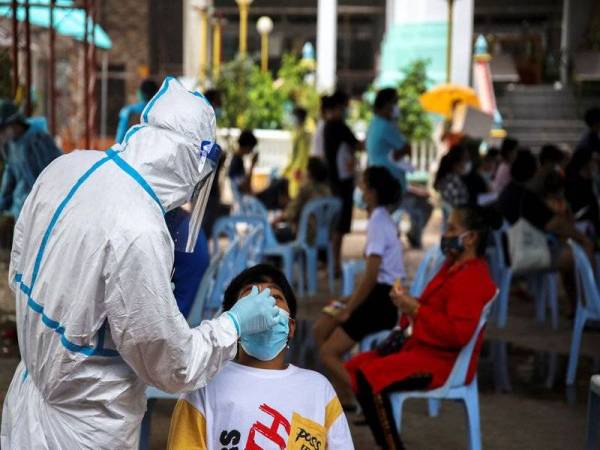 Seorang pekerja penjagaan kesihatan mengambil sampel hidung dari individu di sebuah kuil berhampiran komuniti kumuh Klong Toey di Bangkok, Thailand. Foto Reuters