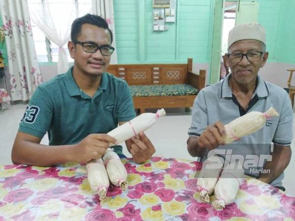 Wagiman (kiri) dan Izham menunjukkan dodol upih yang dibuat oleh keluarganya sejak 20 tahun lalu.