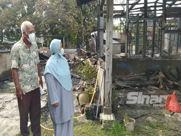 Bahudin dan Salamiah melihat keadaan rumah mereka yang musnah dalam kebakaran di Kampung Padang Tembak di sini pada Selasa.