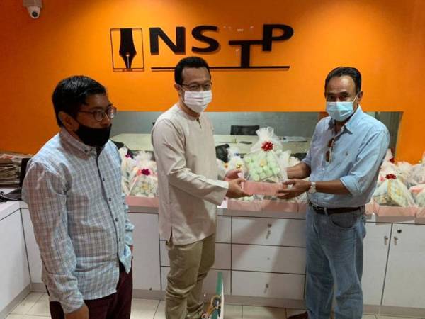 Noor Azizi (tengah) menyampaikan sumbangan biskut raya kepada wakil media yang hadir di pejabat NSTP Kota Bharu pada Selasa.